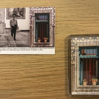 Dois ímanes de geladeira, um com fotografia a preto e branco e texto, outro com imagem de janela decorada com azulejos e plantas.