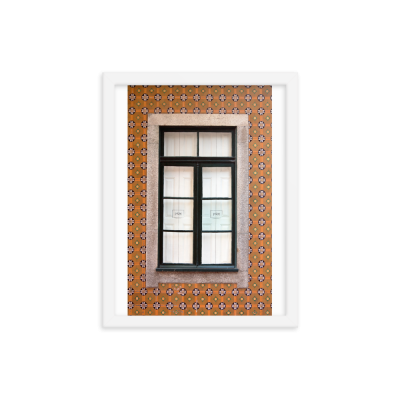 Quadro branco com uma imagem de janela preta numa parede de azulejos laranja com padrão floral.