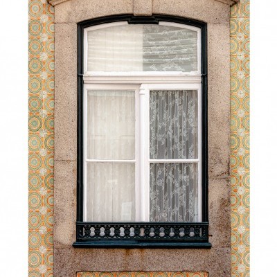 Janela branca de madeira com moldura de pedra e guarda-corpo preto em parede revestida de azulejos amarelos e verdes