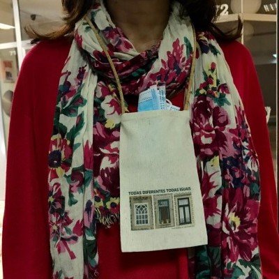 Pano de algodão cru com imagem de portas e texto pendurado no pescoço com camisola e cachecol floral.