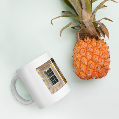 Copo branco com imagem de janela e ananás maduro sobre fundo azul claro