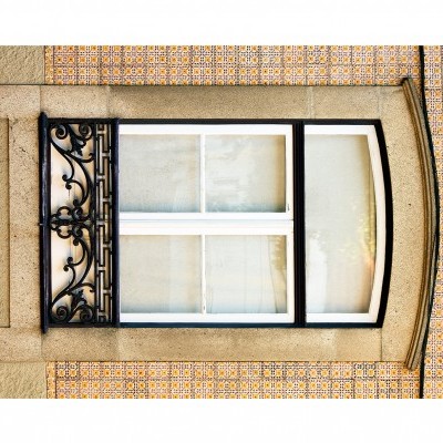 Janela branca com vidro e grade preta em parede de azulejos