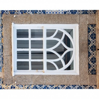 Janela branca com vidro dividido em parede com azulejos azuis e brancos