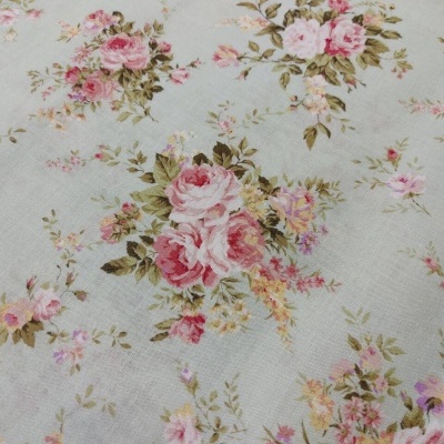 Tecido florido em tons de rosa e verde sobre fundo claro