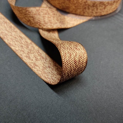 Fita têxtil castanha entrelaçada sobre pano cinzento escuro