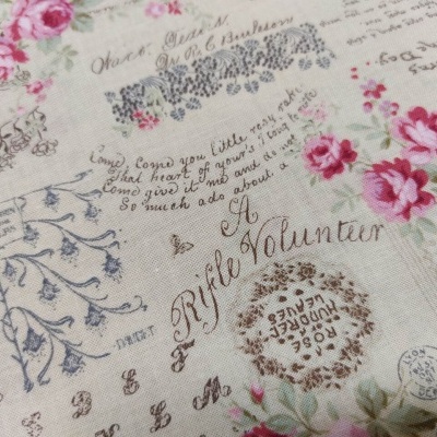 Tecido decorativo com texto manuscrito e padrão floral com rosas cor-de-rosa
