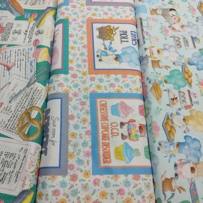 Três rolos de tecido com padrões coloridos de doces, receitas e coelhos na cozinha