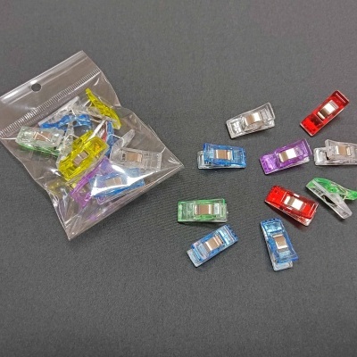 Pregadores de plástico coloridos translúcidos e saco plástico sobre superfície cinza