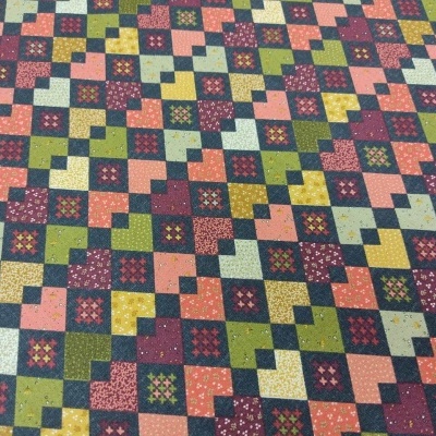 Tecido com padrão geométrico patchwork em várias cores e detalhes florais