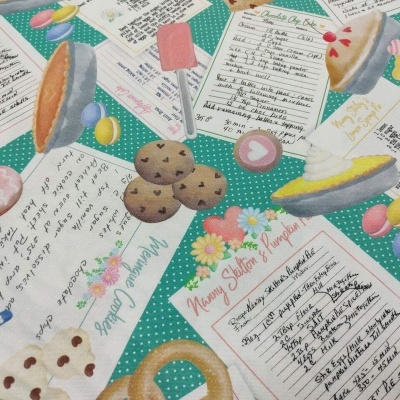 Tecido com receitas manuscritas e ilustrações de doces sobre fundo verde com bolinhas brancas