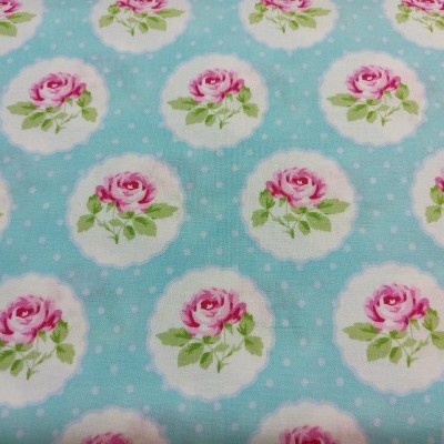 Tecido azul claro com estampa de rosas cor-de-rosa dentro de círculos brancos e bolinhas brancas