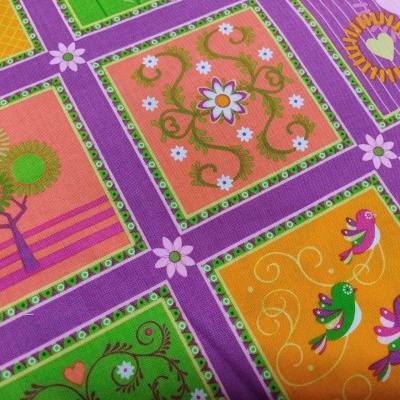 Tecido com padrão floral e pássaros em quadrados coloridos roxos, verdes, laranja e amarelos