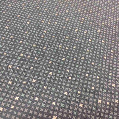 Tecido com padrão de pequenas estrelas em tons pastel sobre fundo cinzento escuro