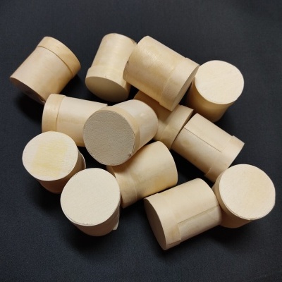 Rolhas cilíndricas de cortiça claras sobre superfície preta