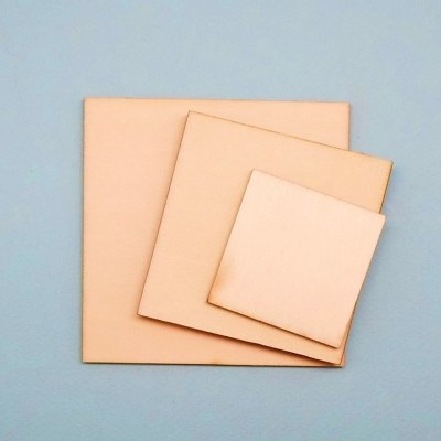 Três quadrados de couro cru com bordas queimadas sobre fundo azul claro