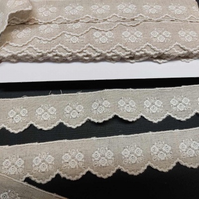 Três fitas de renda bege com flores brancas em superfície preta e branca