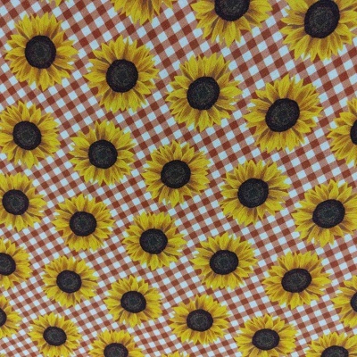 Tecido com padrão de girassóis e fundo xadrez castanho e vermelho