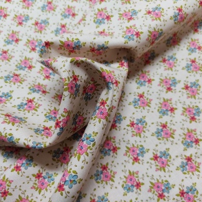 tecido branco com padrão de flores pequenas em rosa, azul e verde