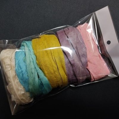 Pacote plástico com faixas de tecido de várias cores e textura enrugada.