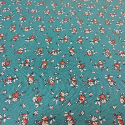 tecido verde-azulado com padrão de pequenas flores brancas e vermelhas