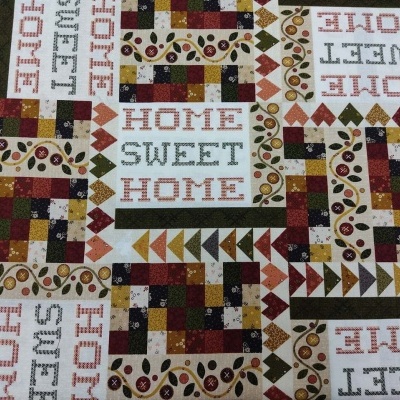 Tecido estampado com padrão patchwork e texto 'HOME SWEET HOME' em várias direções