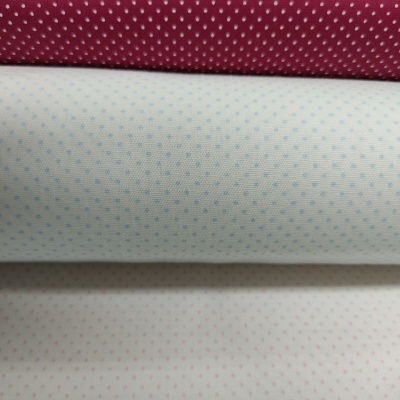 Três rolos de tecido com padrão de pequenos pontos em vermelho, azul e vermelho