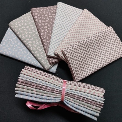 Pedaços de tecido algodão com padrões e fita rosa sobre fundo preto