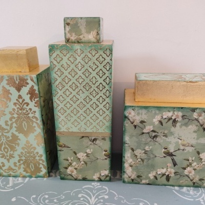 Conjunto de três caixas decorativas verdes com padrões florais e geométricos em dourado e bege