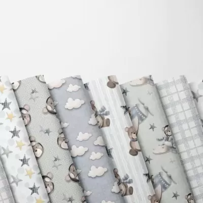 Tecidos em rolos com padrões de estrelas, ursos, nuvens e riscas em tons neutros