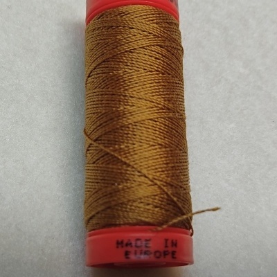 Carretel de linha castanha com extremidades vermelhas e inscrições, sobre fundo cinzento claro