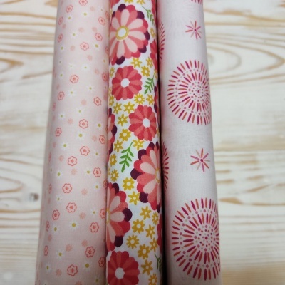 Rolos de tecido com padrões florais coloridos sobre madeira clara