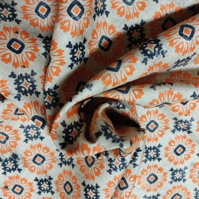 Tecido com padrão geométrico laranja e azul sobre fundo bege