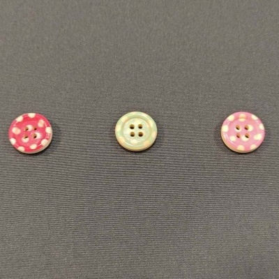 três botões coloridos sobre tecido cinza