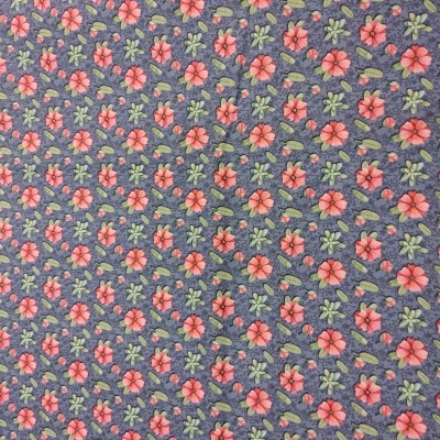 Tecido azul com flores vermelhas e folhas verdes em padrão repetido.