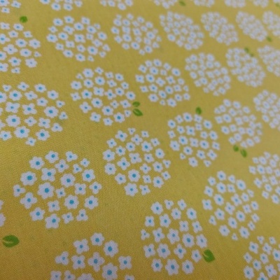 tecido amarelo com padrão floral branco e folhas verdes