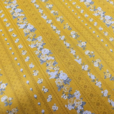Tecido amarelo com padrão floral azul e branco em faixas verticais