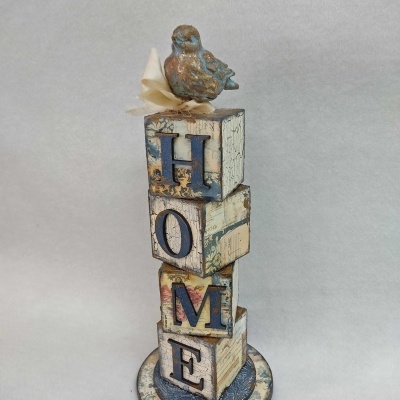 Escultura decorativa com blocos azuis e creme e pássaro no topo