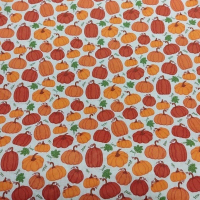 Tecido com padrão de abóboras laranja, amarelas e vermelhas com folhas verdes