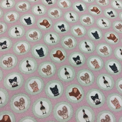 Tecido rosa claro com padrões de círculos contendo desenhos de cães, gatos, coelhos e patos