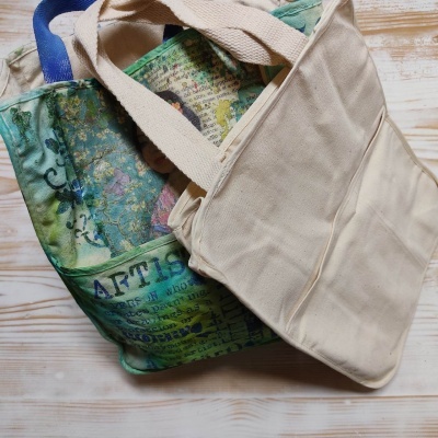 Duas malas de lona, uma branca e uma colorida com padrão artísticos e texto parcial
