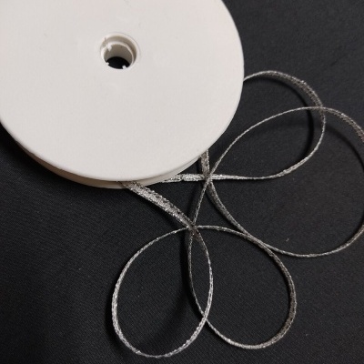 Rolo de fita prateada brilhante em suporte branco sobre fundo preto