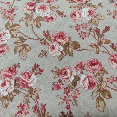 Tecido com padrão floral em tons de rosa e verde sobre fundo bege