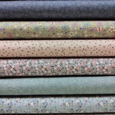Oito rolos de tecidos com padrões florais, geométricos e de casas em cores suaves empilhados