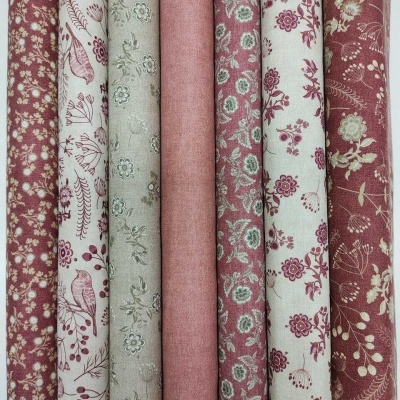 tecidos enrolados com padrões florais e pássaros em tons vermelhos, creme e bege