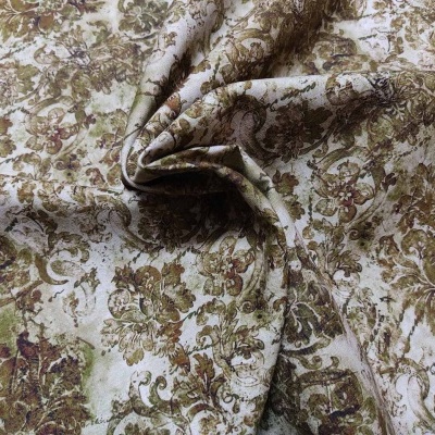 Tecido floral em castanho e verde sobre fundo bege com dobras