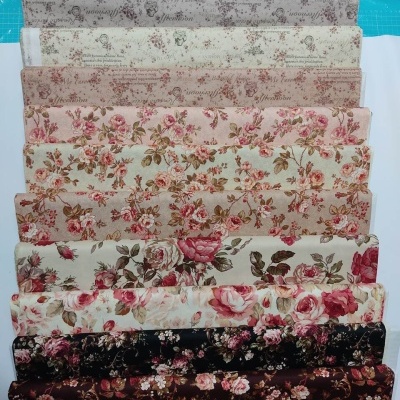 Tecidos com padrões florais e de texto em várias cores empilhados em fila