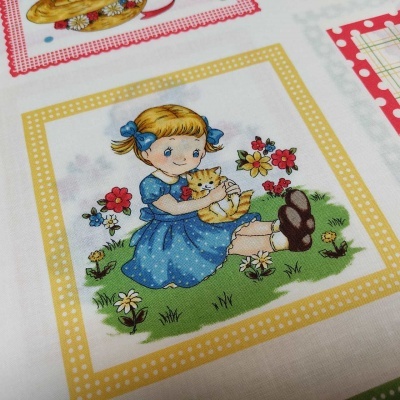 Tecido estampado com menina de vestido azul e gato numa moldura amarela