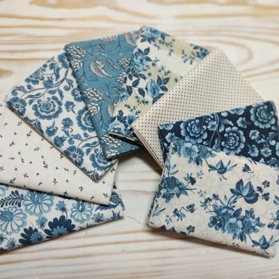 Pedaços de tecido com padrões florais azuis e brancos sobre madeira clara