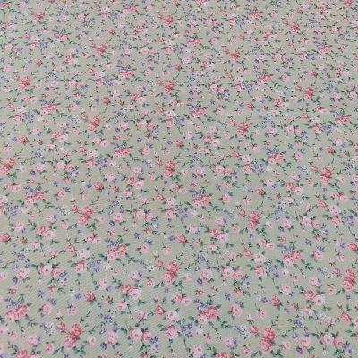 Tecido com padrão floral rosa e lilás sobre fundo verde claro