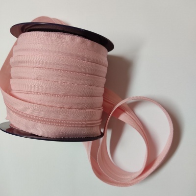 Rolo de fita rosa clara em carretel preto sobre fundo branco